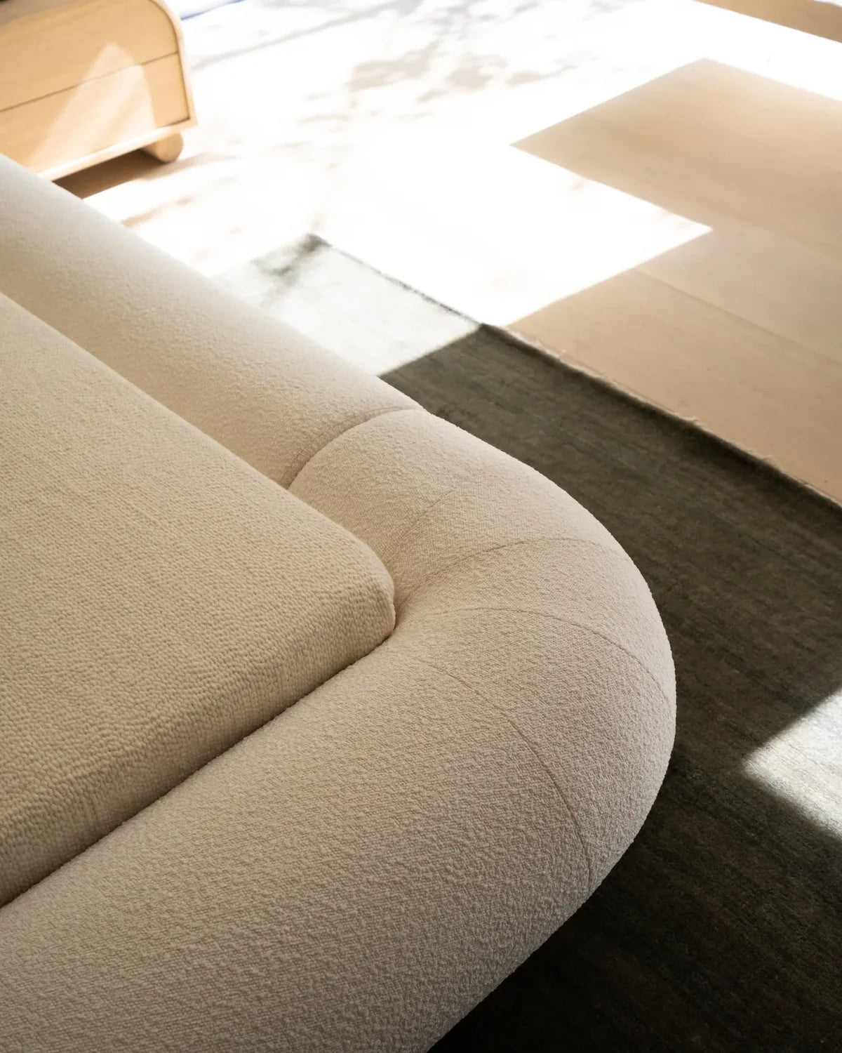 Close-up of VELAR Sculptural Bed Frame in off white showing textured upholstery and rounded padded edge